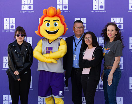 Mascot with President Pendergrass and naming contest winners with SJC purple background.