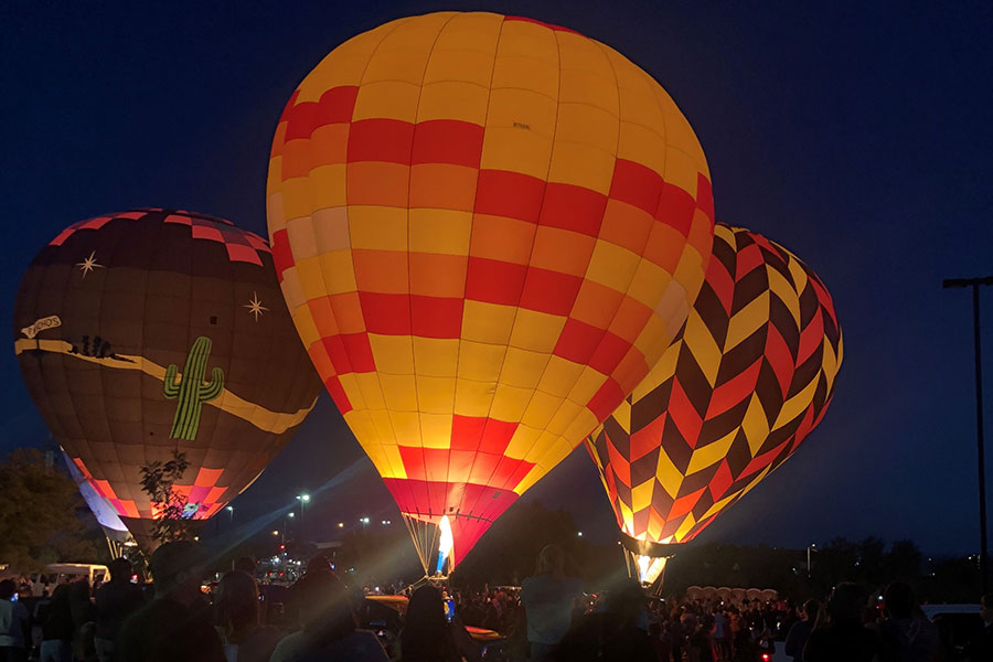 Three hot air balloon in full burn with their yellow and red tops glowing.