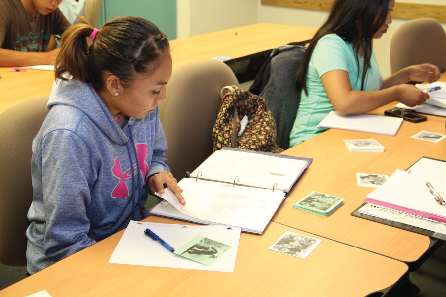 Students sitting at desk looking through notebooks