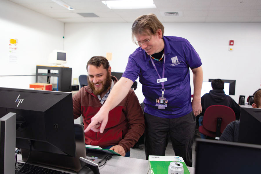 SJC Instructor pointing to computer screen, alongside student.