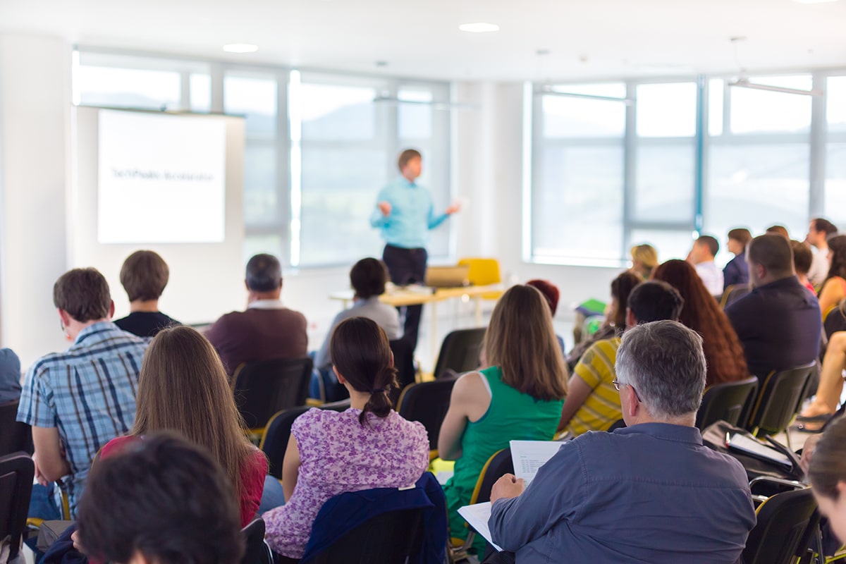 Professionals in a classroom listening to instructor's lecture.