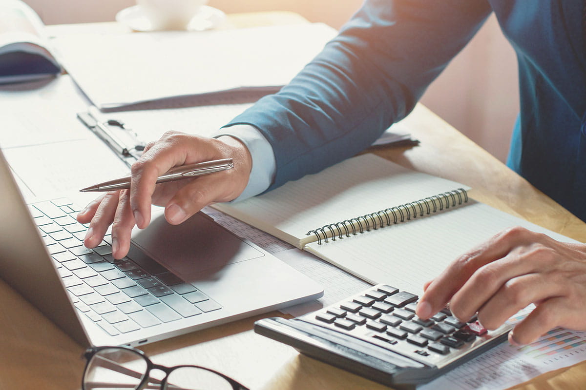 Accounting professional working on laptop and calculator.