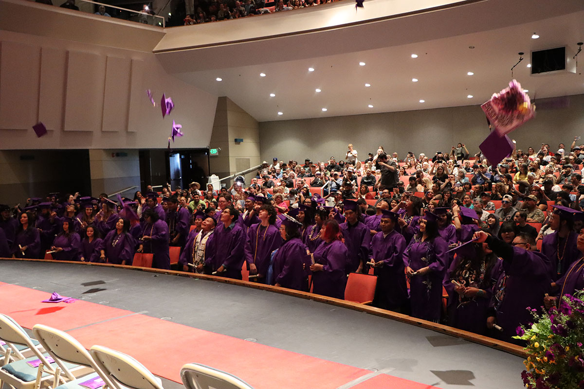 Ace Center graduating class in full gowns throwing caps