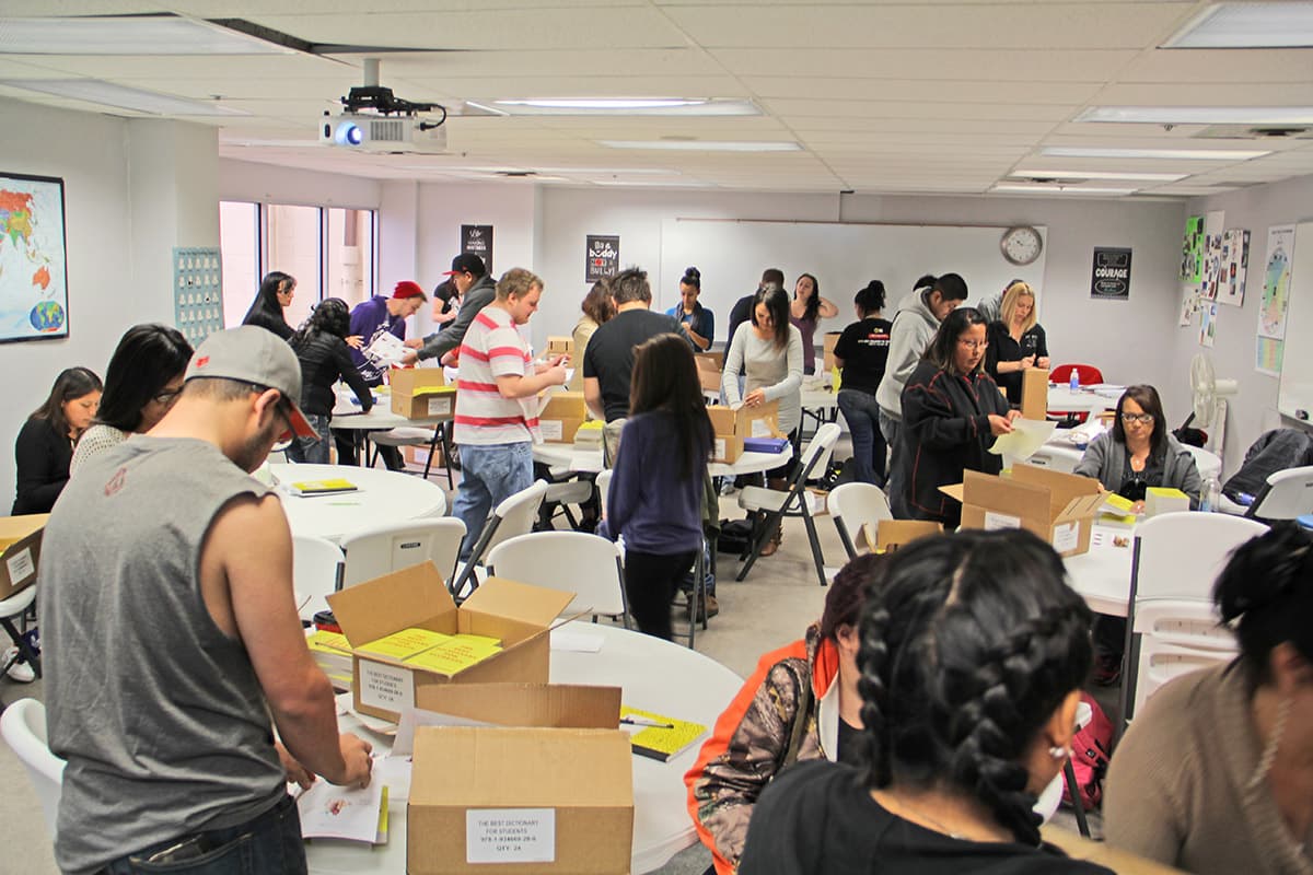 Students in the adult education program work together unpackaging and labeling all the shipments of dictionaries.