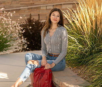 Person sitting on concrete ledge outside.