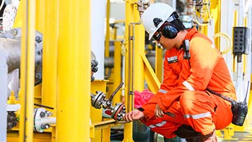 Person wearing orange coveralls and white hardhat