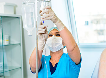 Person wearing scrubs, adjusting IV medication.