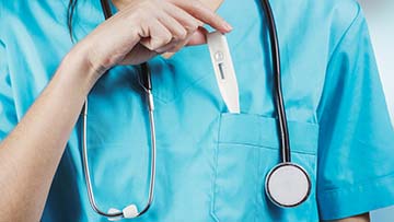 Person putting thermometer in pocket of scrubs