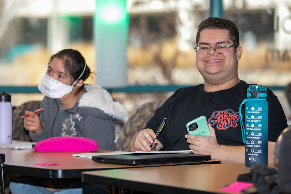 Two San Juan College CLEAR program students taking notes in class