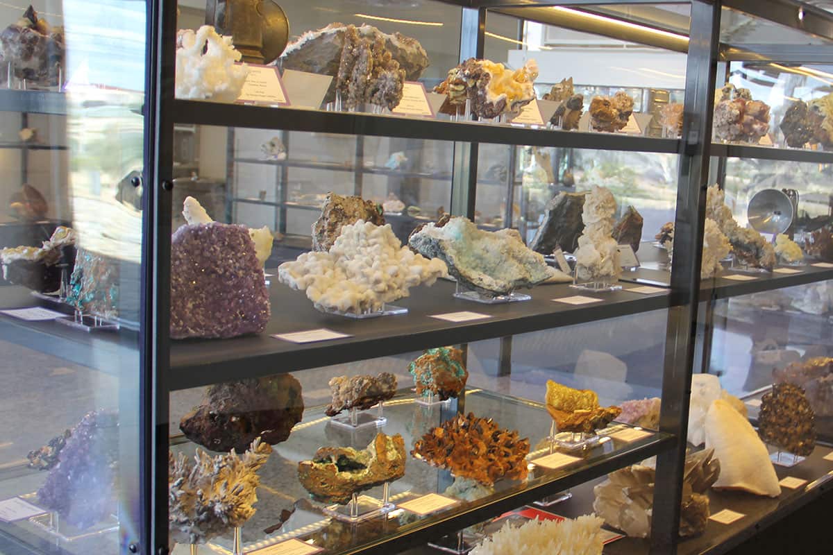 A glass display case with shelves of geodes and crystals