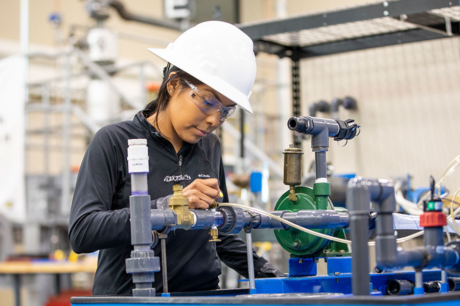 An individual in a hard hat inspects valves and equipment