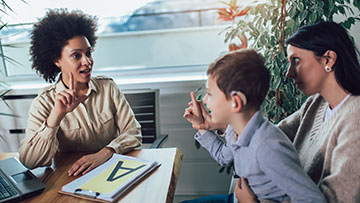 Teacher teaching two students sign language