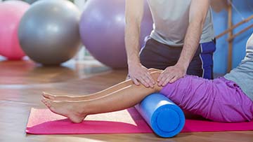 Physical therapist helping a patient with legs up on a roller