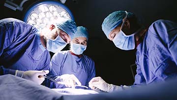 Three people performing surgical procedure.