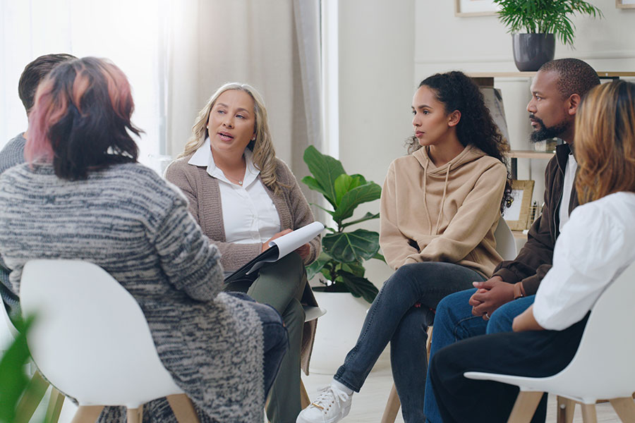 A therapist leading a group counseling session with a diverse group of people sitting in a circle