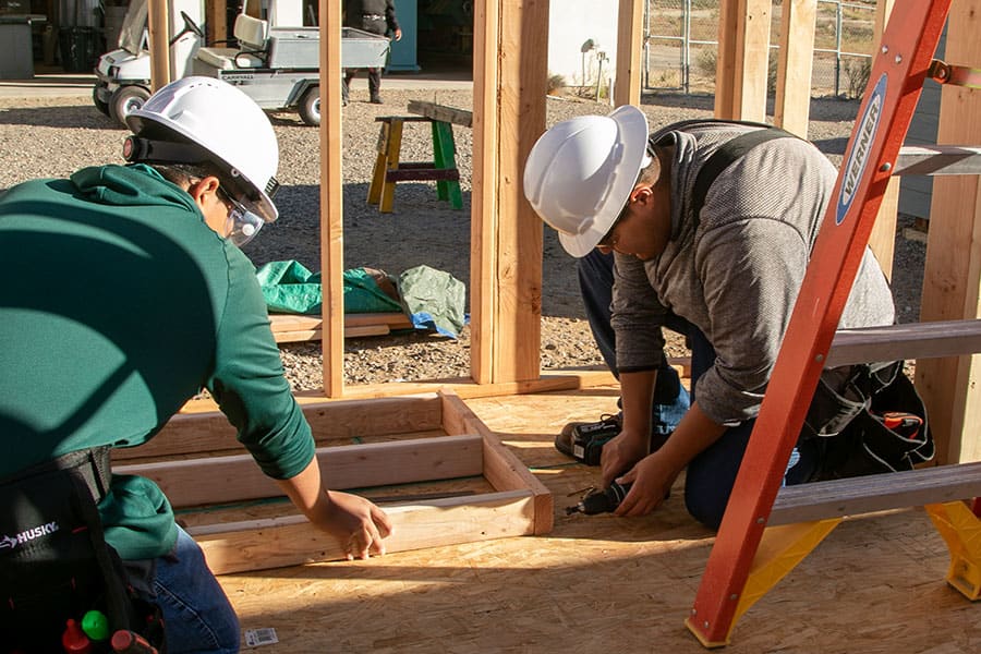 Two San Juan College students working on framing a building