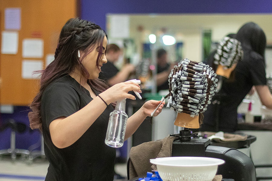 A San Juan College student practicing setting curls on a wig