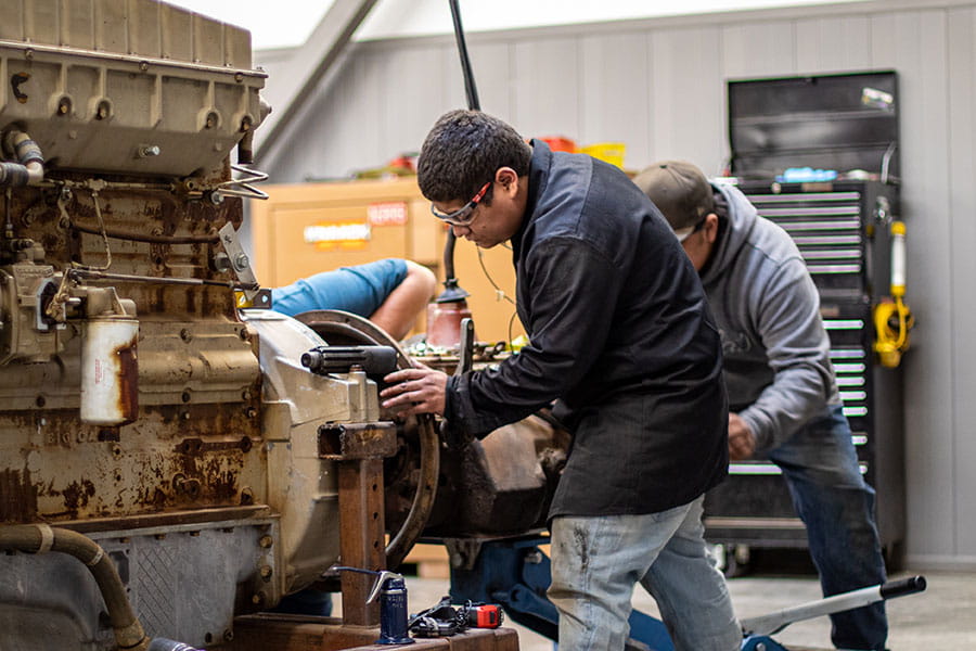 San Juan College students working on a large diesel engine