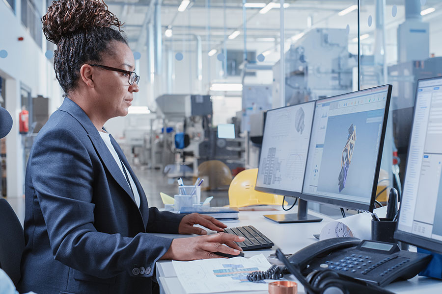 An individual dressed in a work suit sits looking at a desktop computer