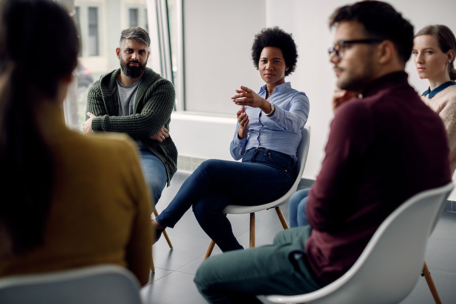 A diverse group of people sitting in chairs in a circle having a discussion