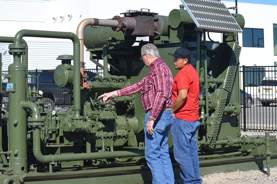 Two individuals look and point at natural gas valves in an outdoor setting