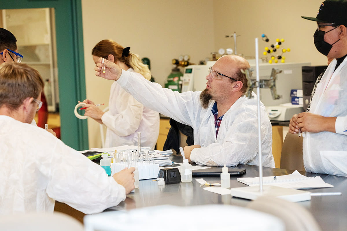 Chemistry students in a Lab working with test tubes and collaborating with instructor