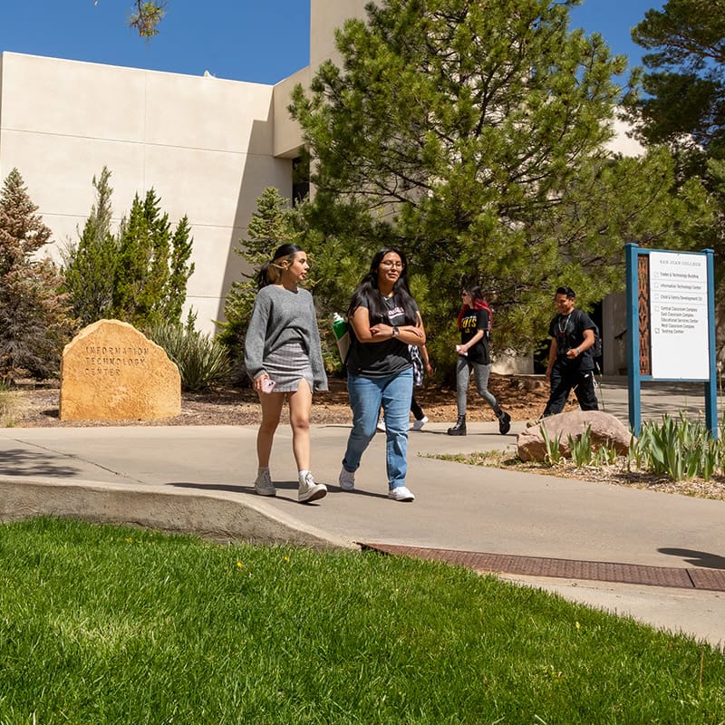 Student walking on the San Juan College Campus near the IT building