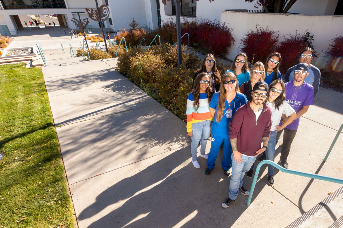 Overhead picture o f 10 SJC students, all wearing sunglasses outside.