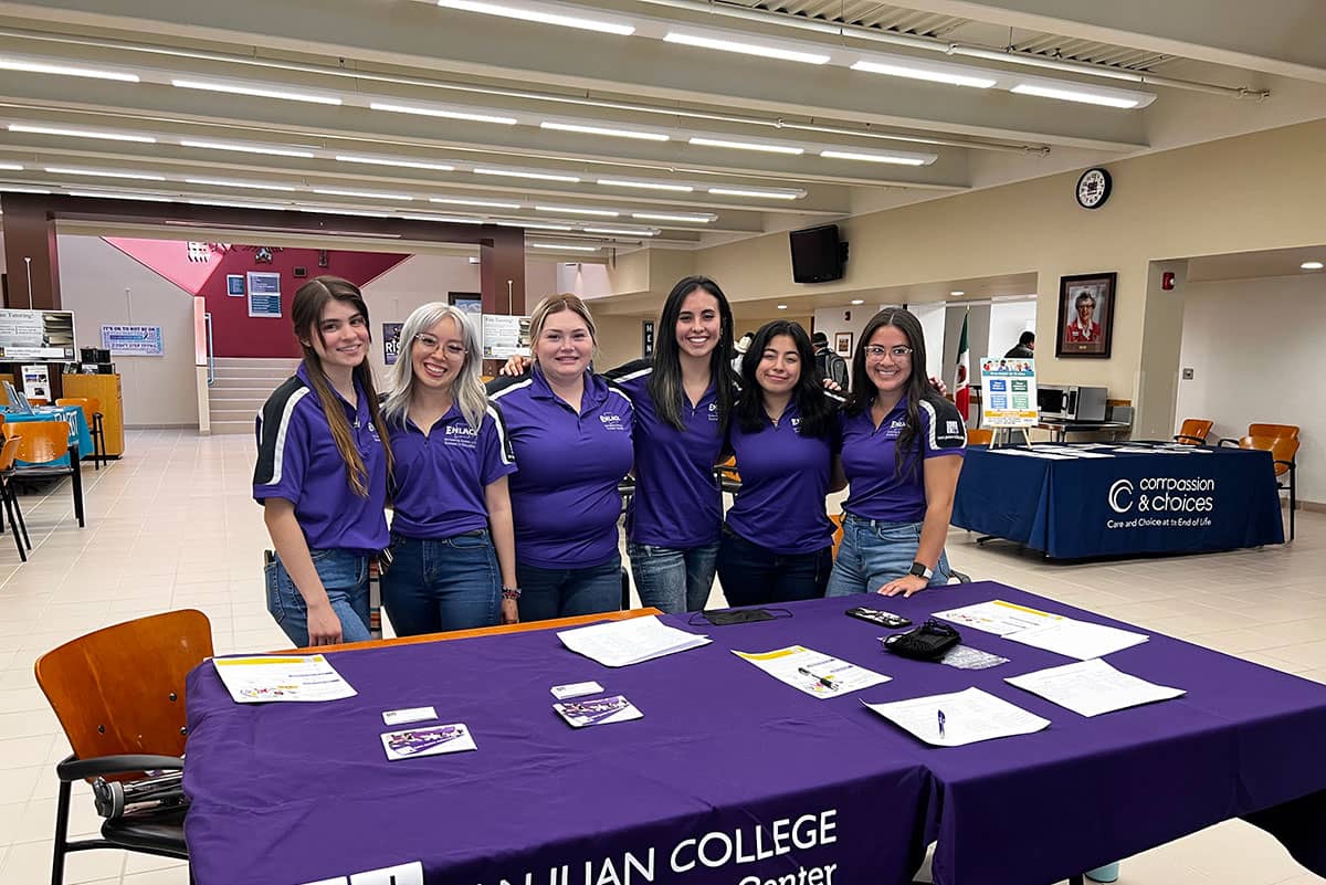 SJC Enlace Ambassadors standing in front of table.