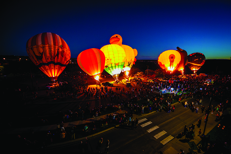 Multiple hot air balloon floating in the SJC parking lot with a large crowd around