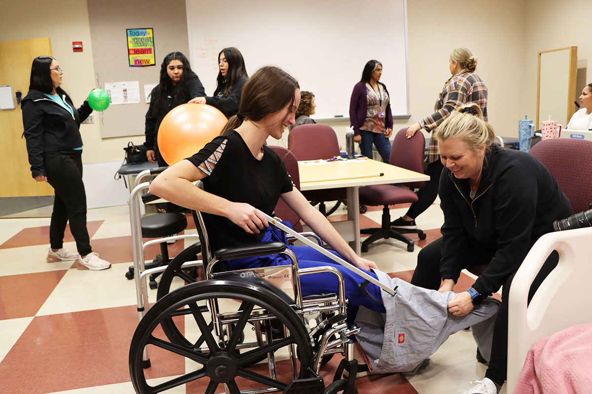 Two San Juan College students utilizing equipment for training in a wheelchair and using stretch bands.